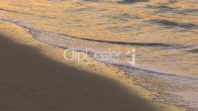 HD Gentle waves on a sandy beach in sunrise, closeup