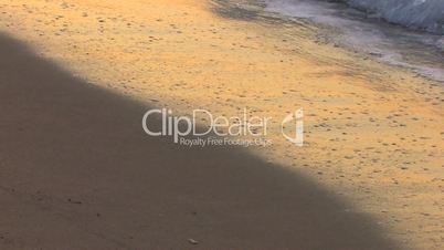 HD Gentle waves on a sandy beach in sunrise, closeup