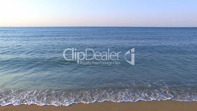 HD Gentle waves on a sandy beach with skyline background