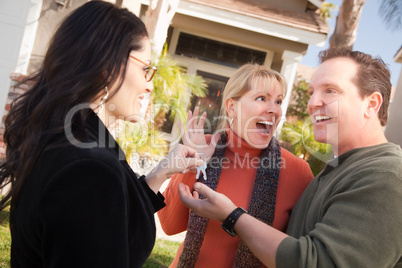 Hispanic Female Real Estate Agent Handing Keys to Excited Couple