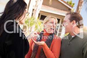 Hispanic Female Real Estate Agent Handing Keys to Excited Couple