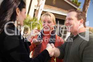 Hispanic Female Real Estate Agent Handing Keys to Excited Couple