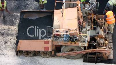 Road construction workers with paving machine