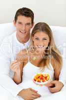 Romaantic couple eating fruit lying on their bed
