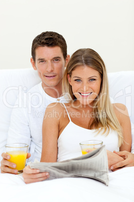 Young couple reading a newspaper and drinking orange juice