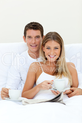 Romantic couple drinking coffee lying on their bed