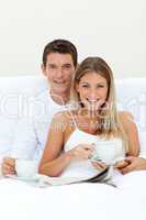 Romantic couple drinking coffee lying on their bed