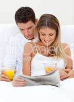 Lovers reading a newspaper and drinking orange juice