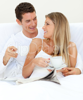 Enamored couple drinking a cup of tea lying on their bed