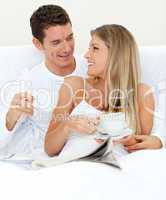 Enamored couple drinking a cup of tea lying on their bed