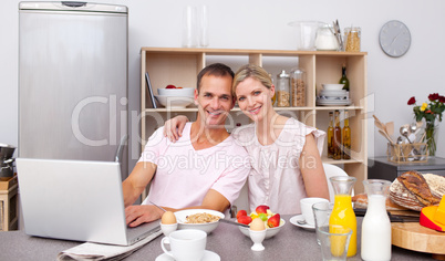 Young couple using a laptop while having breakfast