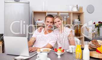 Young couple using a laptop while having breakfast