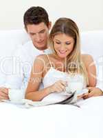Romantic couple reading a newspaper and drinking coffee