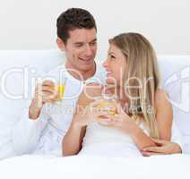 Intimate couple drinking orange juice lying on their bed