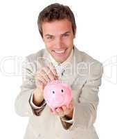 Smiling young businessman saving money in a piggy-bank