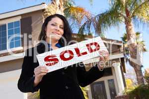 Attractive Hispanic Woman Holding Sold Sign In Front of House