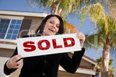 Attractive Hispanic Woman Holding Sold Sign In Front of House