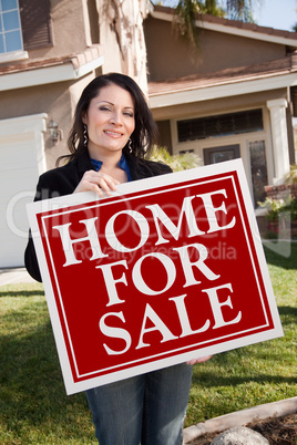 Hispanic Woman Holding Real Estate Sign In Front of House