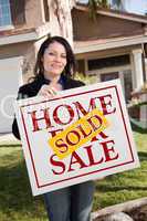 Woman Holding Sold Real Estate Sign In Front of House