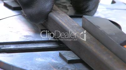 HD Circular saw blade teeth coming through a steel section, closeup