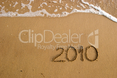 Year 2010 written on the sand