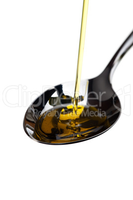 Olivenöl wird über einen Löffel gegossen