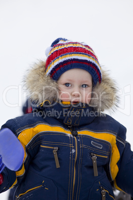 child with shovel look at you in winter background