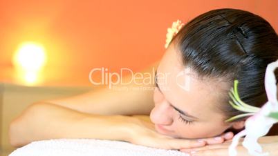 Woman in spa with flower in her hair looks at camera