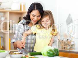 child cutting vegetables with her mother