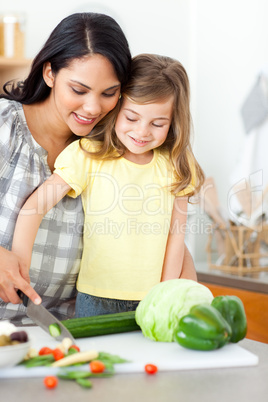 girl cutting vegetables with her mother