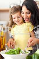 mother helping her daughter prepare salad