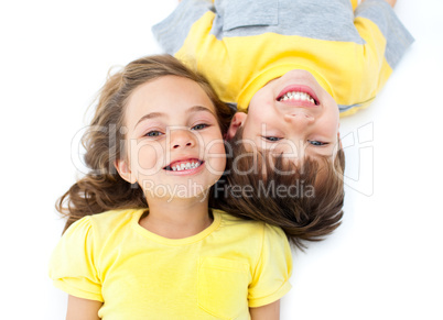 Smiling siblings lying on the floor