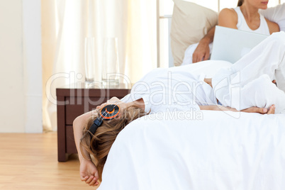 Cute boy listening music lying on bed