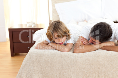Earing father talking with his son lying on bed