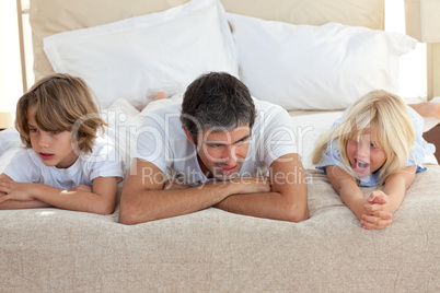 Father and his children talking lying on bed