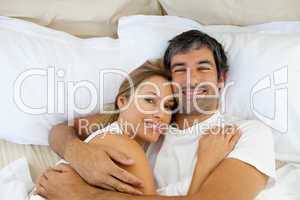 Smiling couple embracing lying in bed