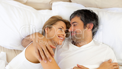 Affectionate couple hugging lying in bed