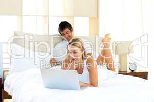 Positive woman using a laptop lying on bed