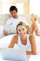 Pretty woman using a laptop lying on bed