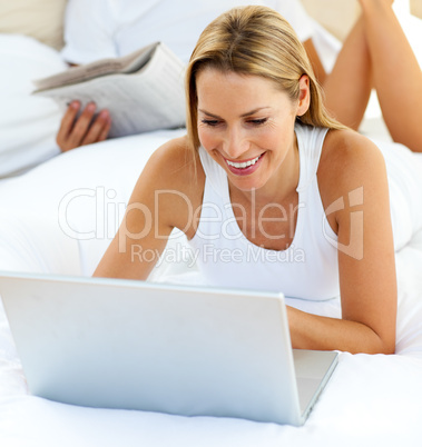 Close-up of woman using a laptop lying on bed