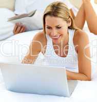 Close-up of woman using a laptop lying on bed