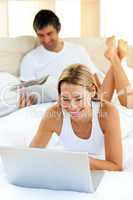 Portrait of woman using a laptop lying on bed