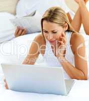 Young woman using a laptop lying on bed