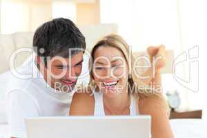 Close-up of lovers using a laptop lying on bed