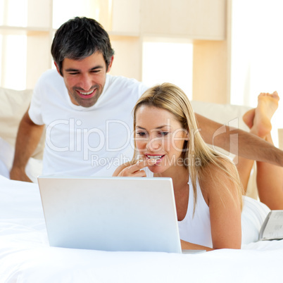 Assertive woman using a laptop lying on bed