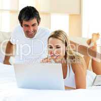 Assertive woman using a laptop lying on bed