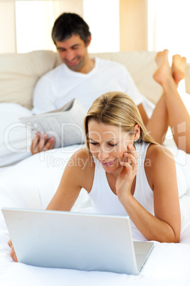 Charming woman using a laptop lying on bed