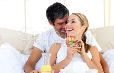 Beautiful couple having breakfast lying in the bed