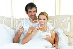 Happy couple drinking coffee lying in the bed