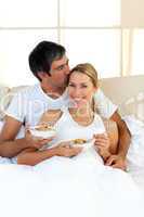 Affectionate couple eating cereals lying in the bed